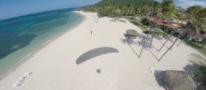 Parapente aterrizando en la arena asistido por otro piloto